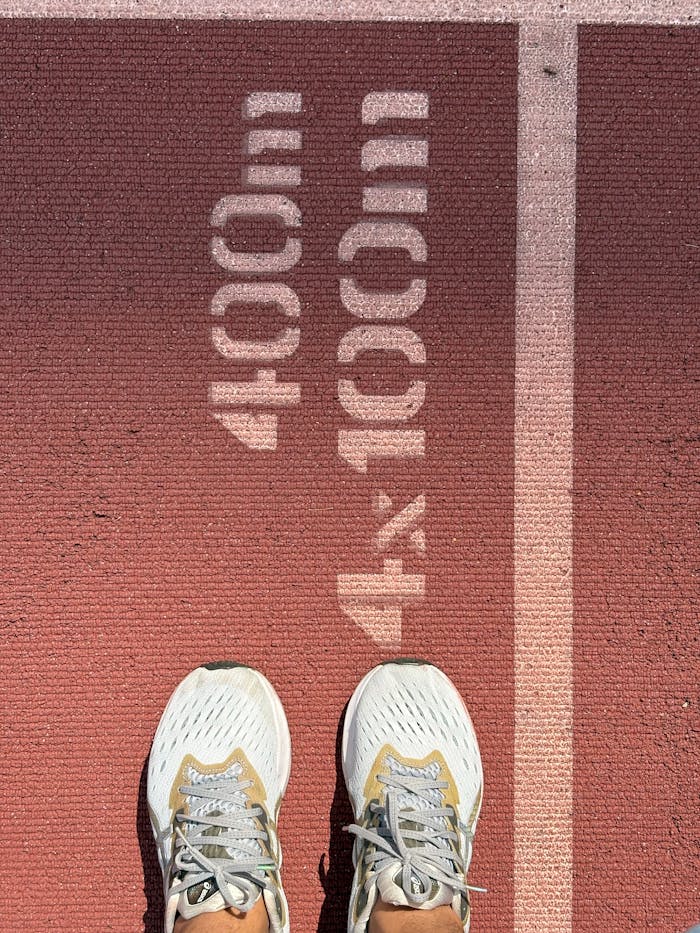 Close-up of running shoes on a track lane indicating 400m and 4x100m distances.